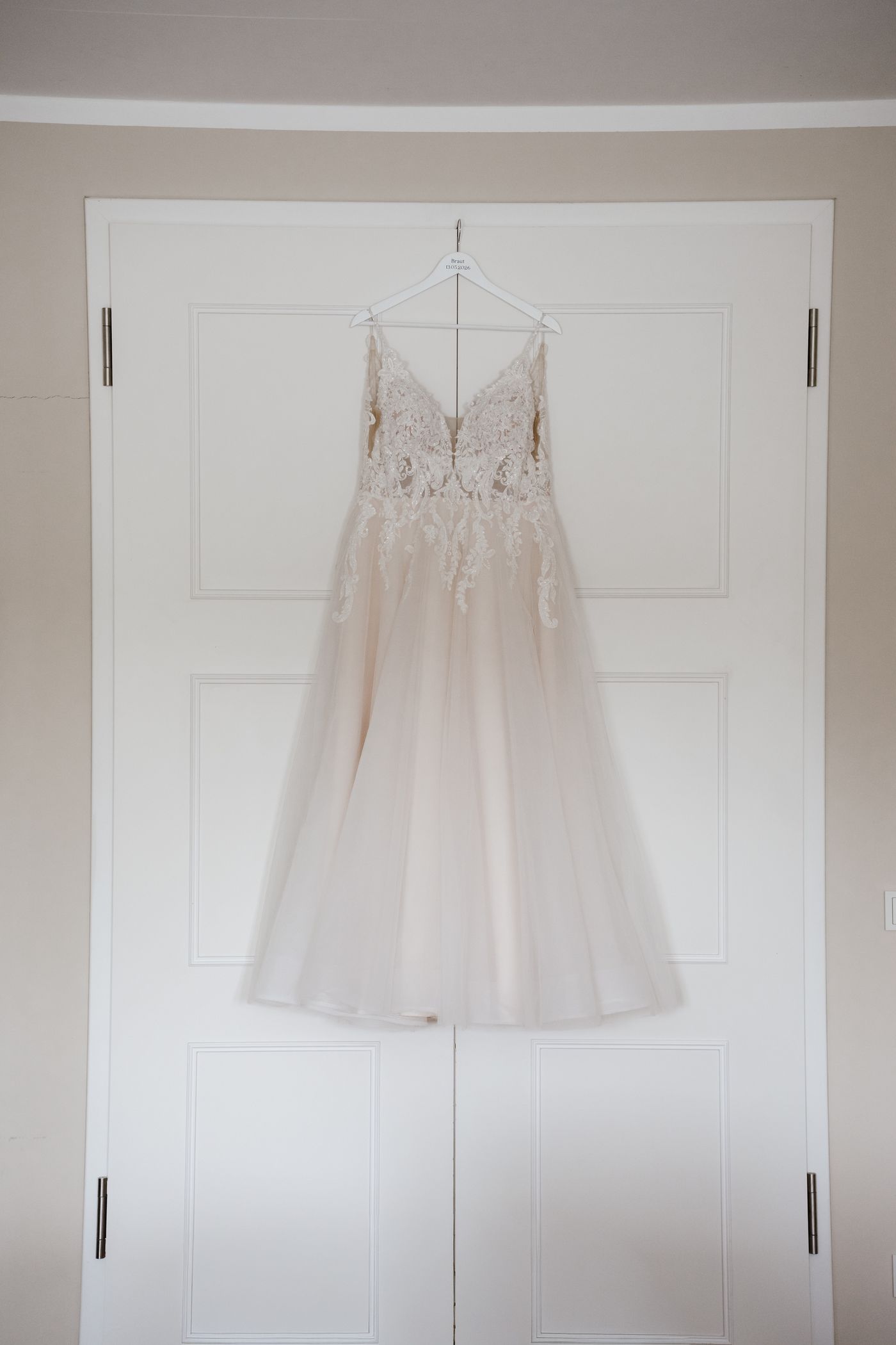 Brautkleid hängt an weißer Tür