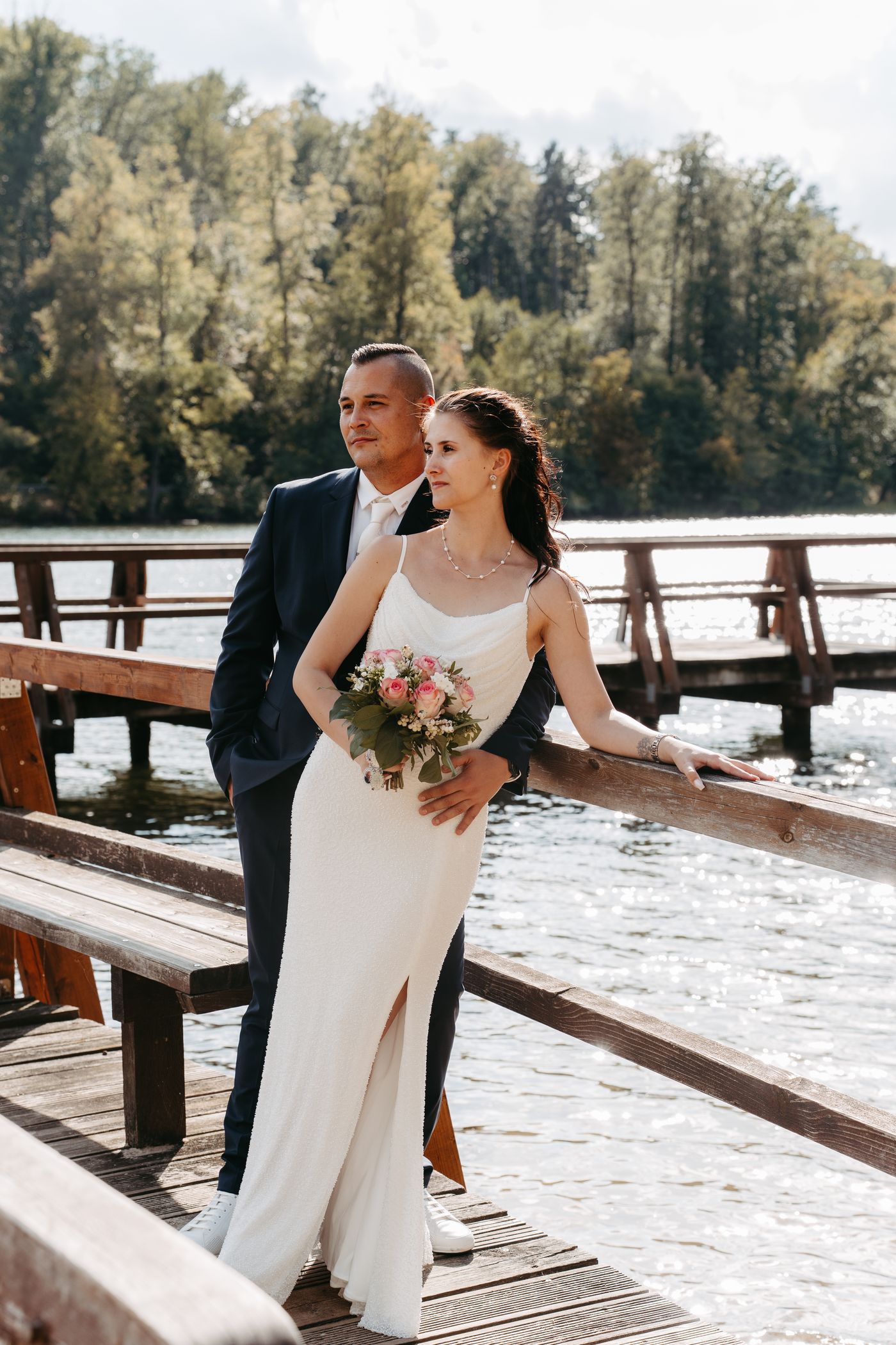 Brautpaar am Steg über dem See mit rosa Brautstrauß