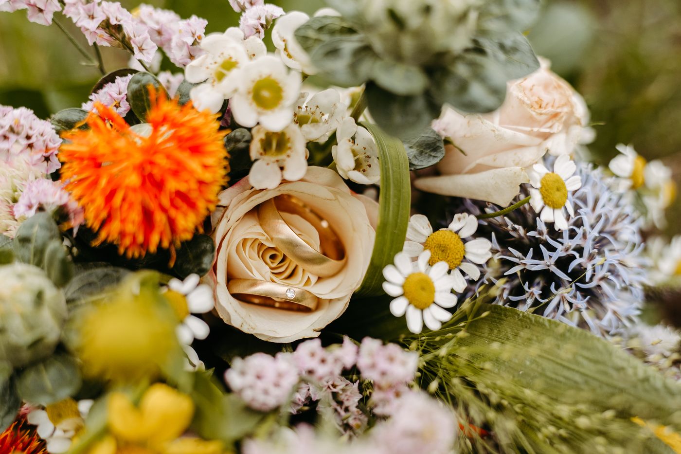 Eheringe in einer Rose – bunter Brautstrauß aus Wildblumen