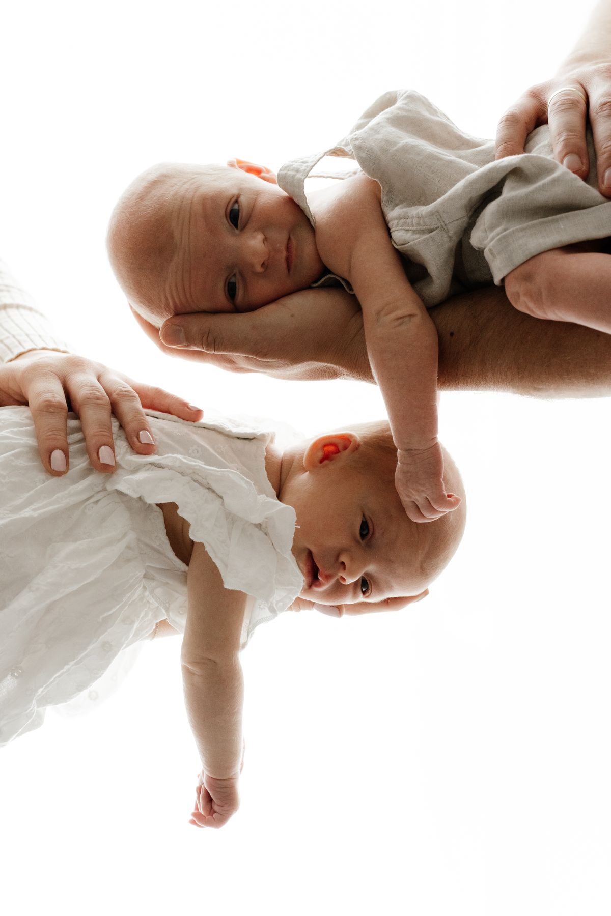 Neugeborenen-Fotografie Berlin – zwei Babys in den Händen der Eltern